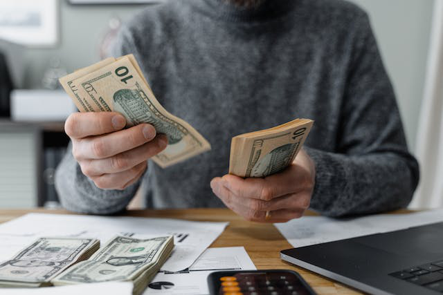 An investor counting dollar bills, depicting financial analysis, and planning for blockchain-based investments