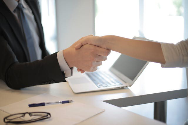 An investment consultant shaking hands with an investor, finalizing a futures trading arrangement