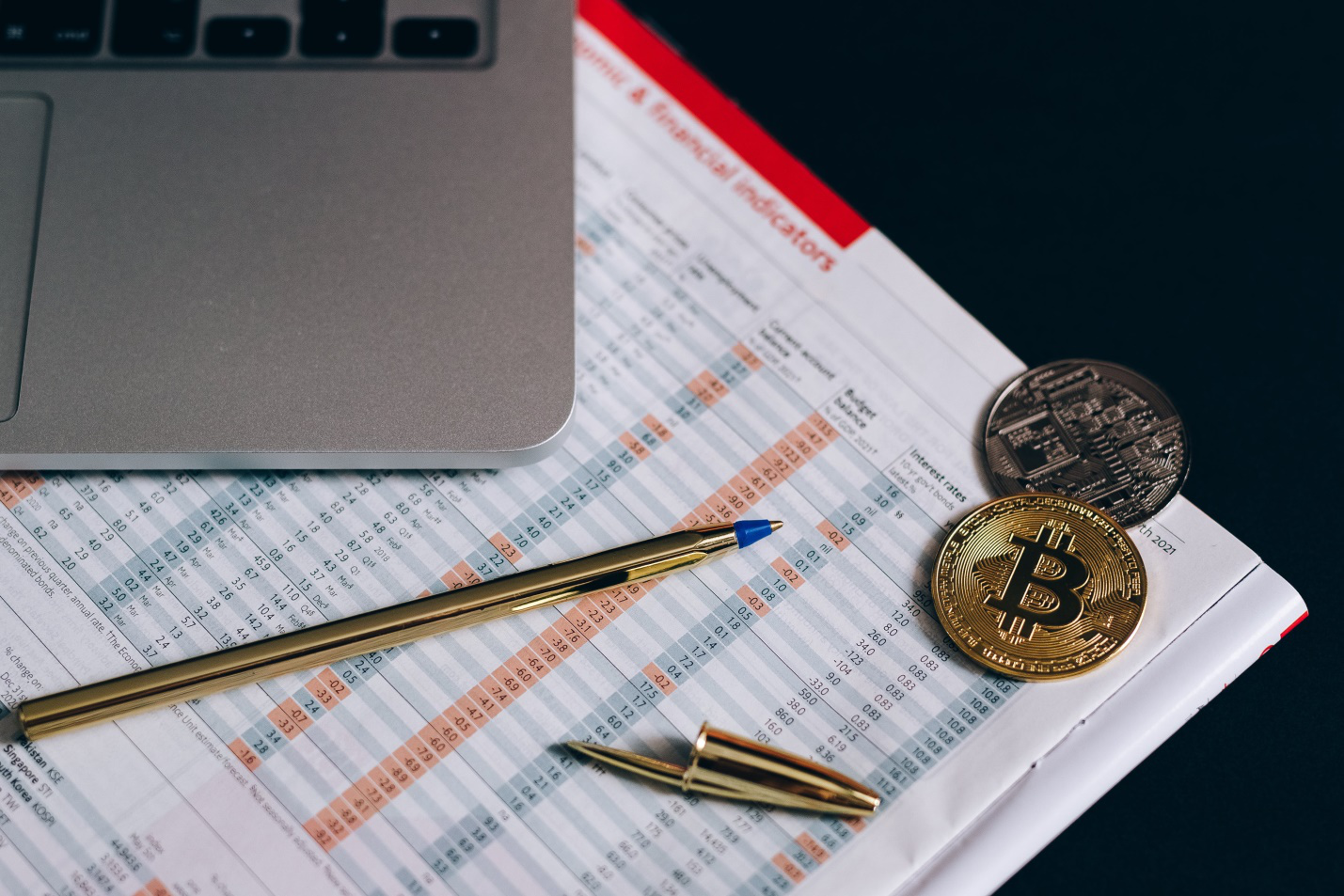a data chart with a gold pen and bitcoins on it 