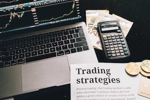 a paper with “trading strategies” printed and placed near a laptop