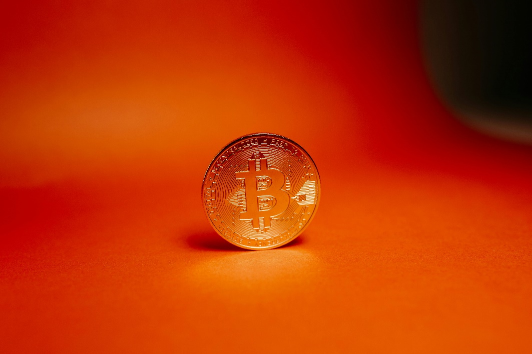 A bitcoin on an orange surface.