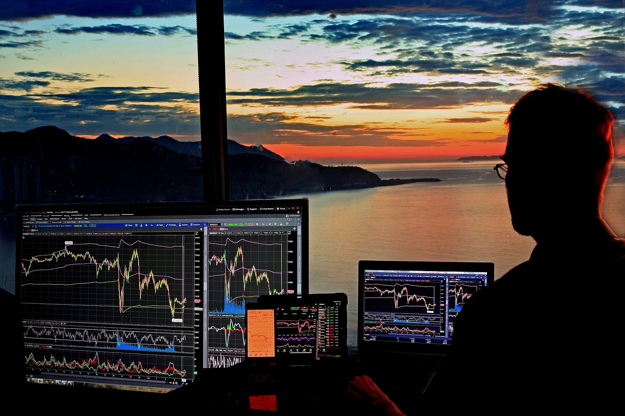 A person analyzing multiple trading charts on screens.