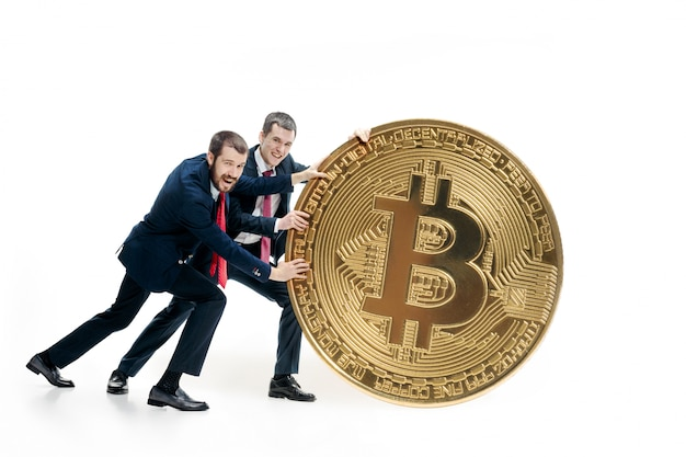 Two businessmen holding a large Bitcoin symbol.