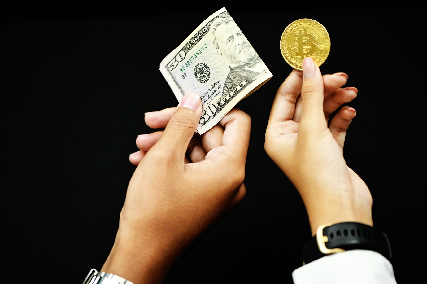 a person holding US dollar bill along with a person holding a gold coin