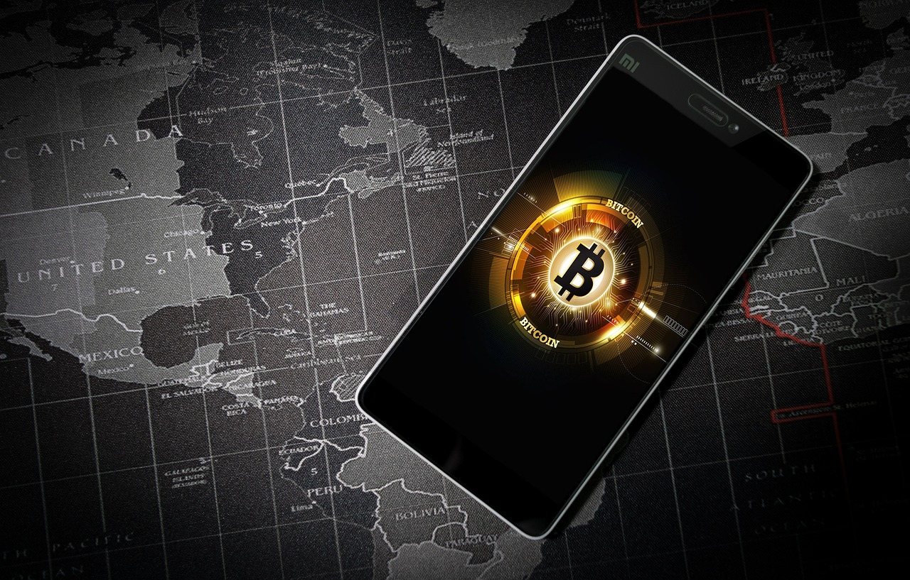 Bitcoin logo displayed on a smartphone over a world map