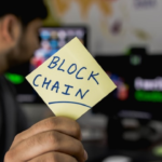 An individual holding a paper with blockchain written on it.