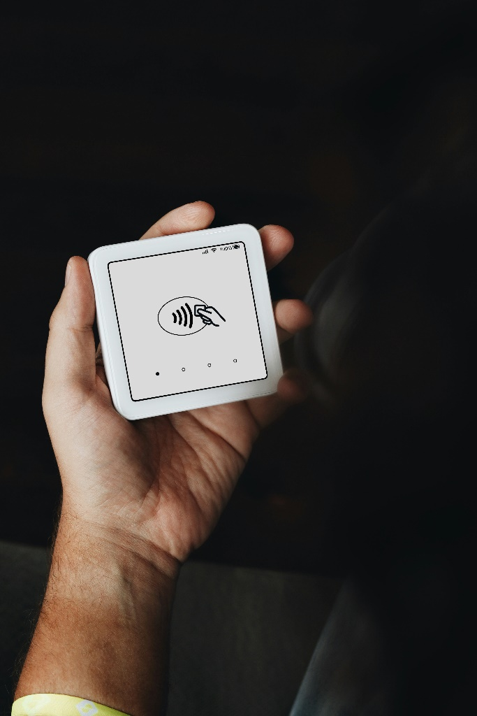 A hand holding a small white card reader.