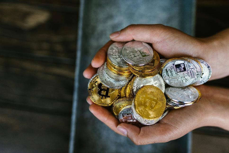 A person holding a pile of various cryptocurrency coins