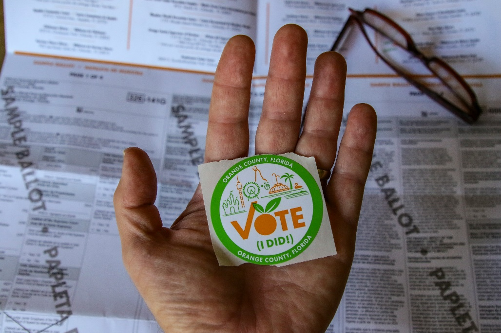 A hand holding an "I Voted" sticker.