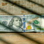 A single US dollar bill lying on a wooden surface.