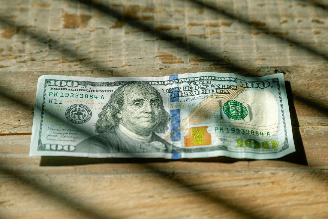 A single US dollar bill lying on a wooden surface.