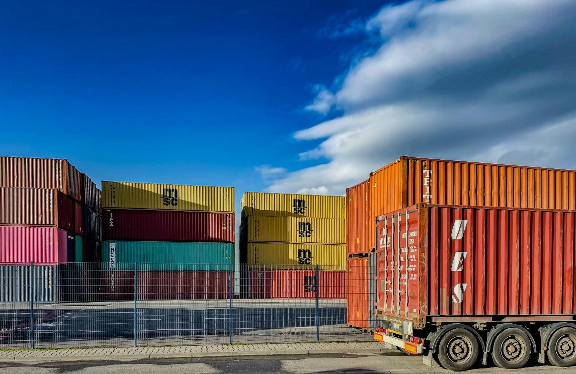 A stack of colorful shipping containers at a port, representing the global supply chain.