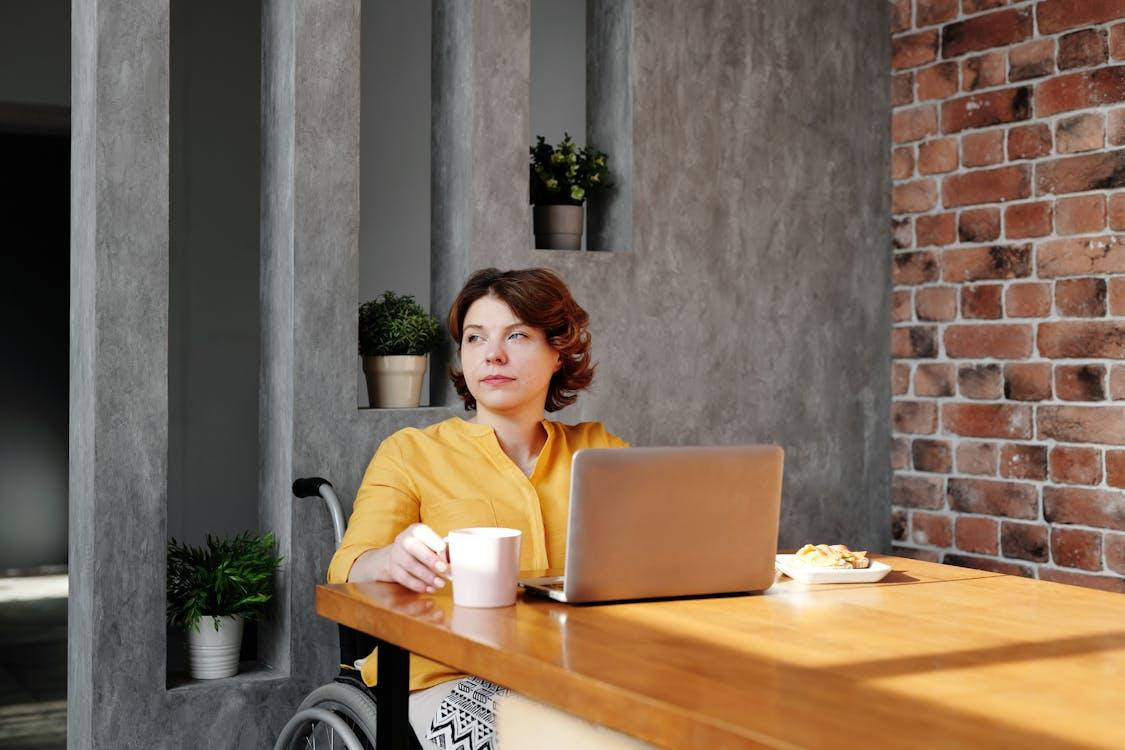 photo of woman sitting by the table while looking away