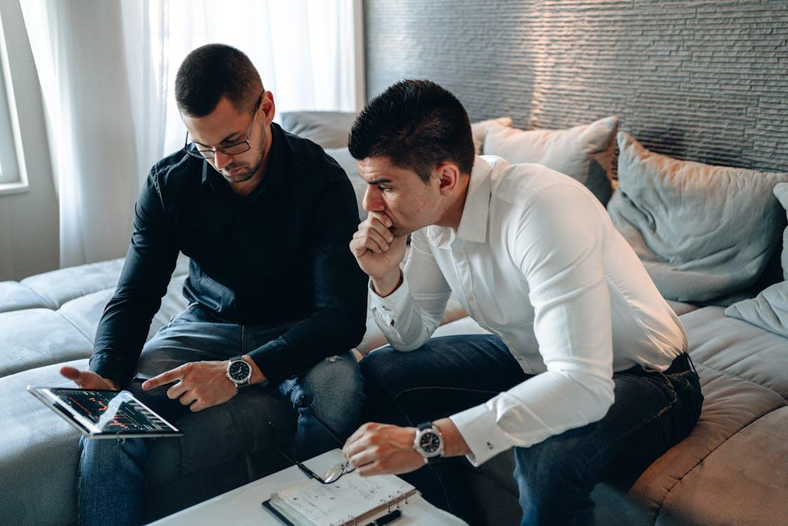 man in black long sleeve pointing at screen of ipad