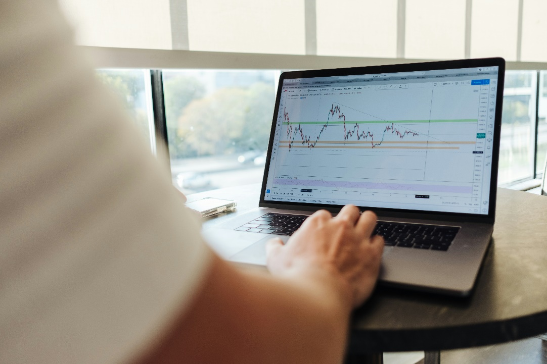 Person working on a laptop at a table, analyzing financial data