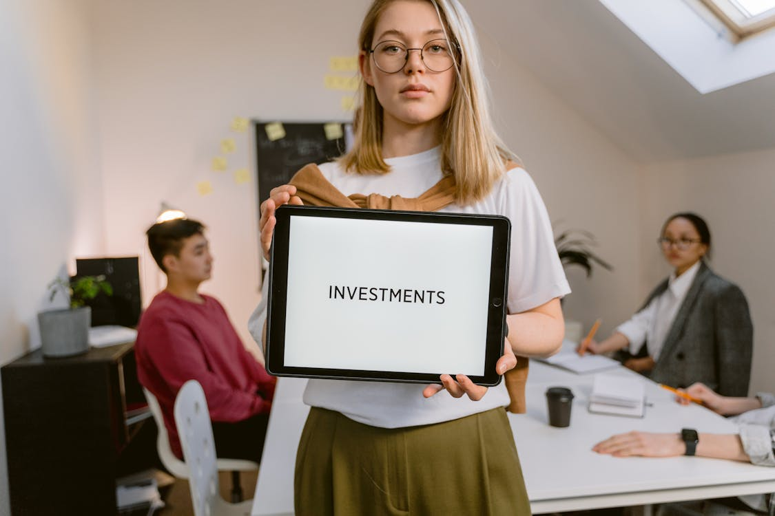 kenson Investments | Supporting Market Awareness – How Kenson Investments Helps Navigate Regulatory Shifts Serious face woman holding a tablet computer with a word "investments" on the screen.