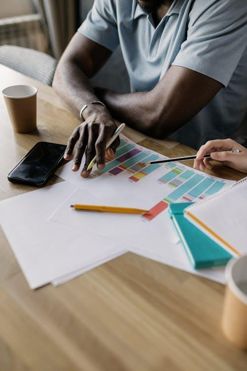 kenson Investments | Senate Sidesteps Trump and Big Tech in New Stablecoin Draft interracial hands with pens on white paper with graph