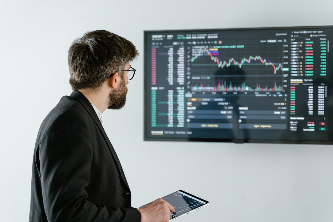 kenson Investments | AI-Driven Trading: Automation and Analytics in Digital Asset Strategy man in black suit jacket holding iPad.