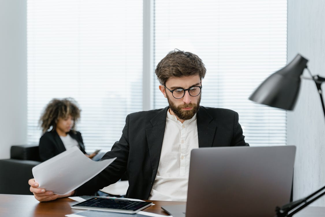 kenson Investments | AI-Driven Trading: Automation and Analytics in Digital Asset Strategy man in black suit jacket holding iPad.