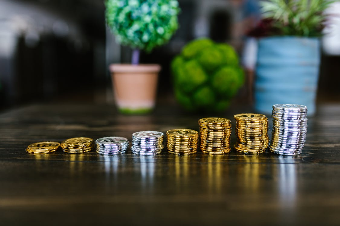 A collection of silver and gold Bitcoin tokens displayed on a wooden table.