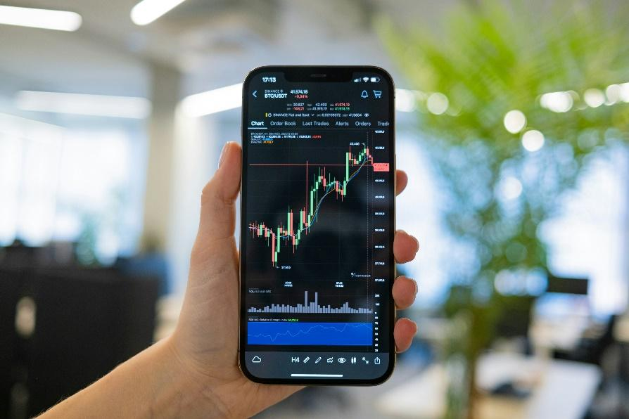 Hand holding smartphone with real-time crypto trading interface open