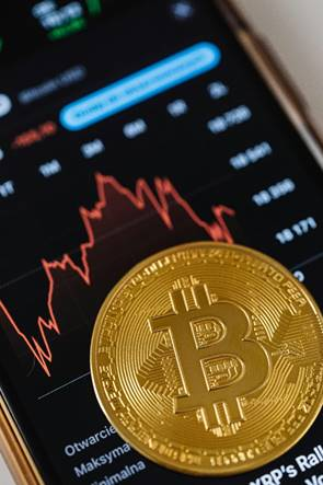 A gold cryptocurrency coin resting on a smartphone screen
