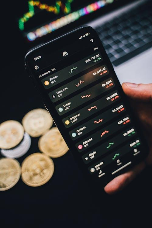 kenson Investments | Bitcoin Ripples Past $106K Amid Middle-East Mayhem—Are We Riding the Wave or Heading for a Drop? A hand holding a smartphone showing a cryptocurrency trading chart.
