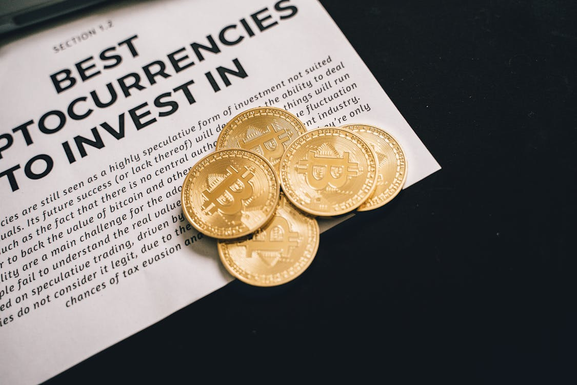 A high-resolution photo of several physical Bitcoin tokens arranged on a newspaper’s page.