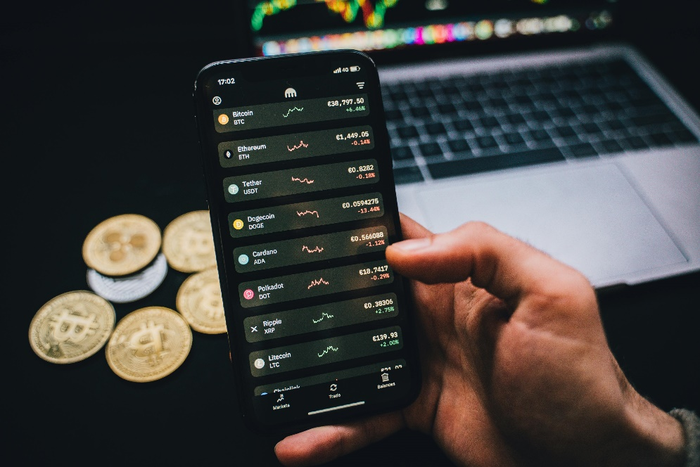 A hand holding a smartphone displaying a cryptocurrency trading application.