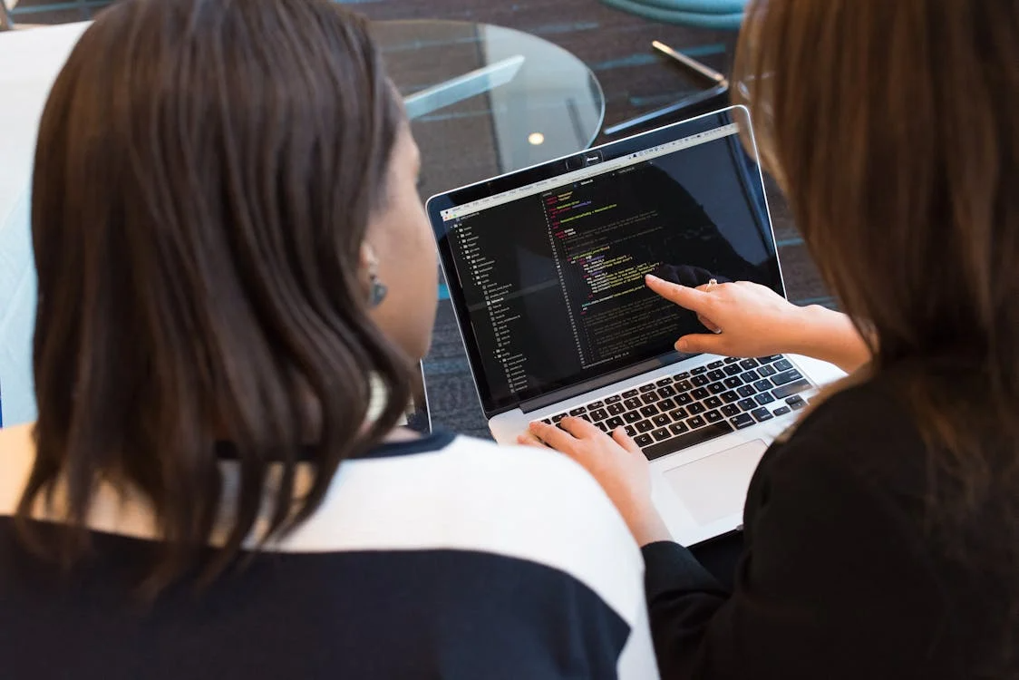 kenson Investments | Tokenized AI Models – Monetizing Machine Learning via Blockchain Female developers coding AI model with blockchain royalty system for automated revenue streams