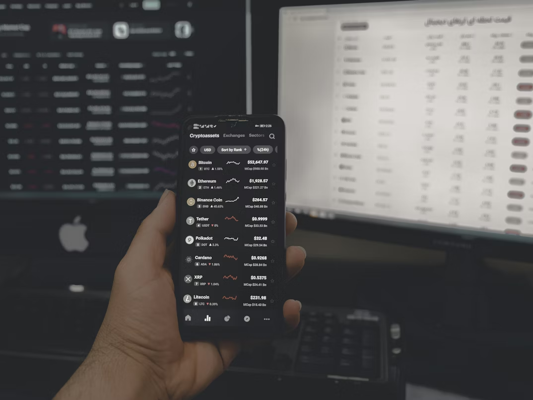 Person holding a smartphone displaying a crypto chart