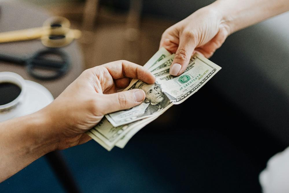 Close-up of hands exchanging US dollar bills