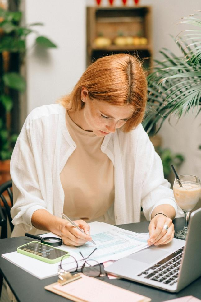 Analyst reviewing financial documents and calculations at a desk with a laptop.
