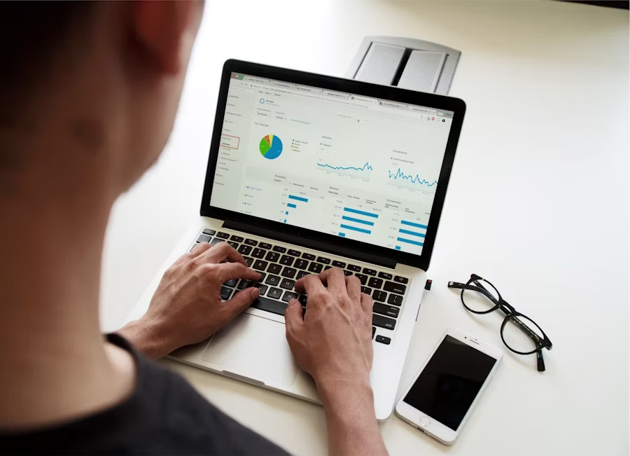 kenson Investments | Tokenized Corporate Actions: What Actually Works in Production Person viewing charts and metrics on a laptop analytics dashboard
