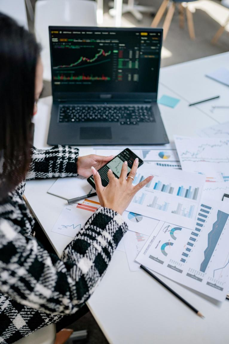 Trader reviewing digital asset price charts on a laptop while analyzing execution data on a mobile device.