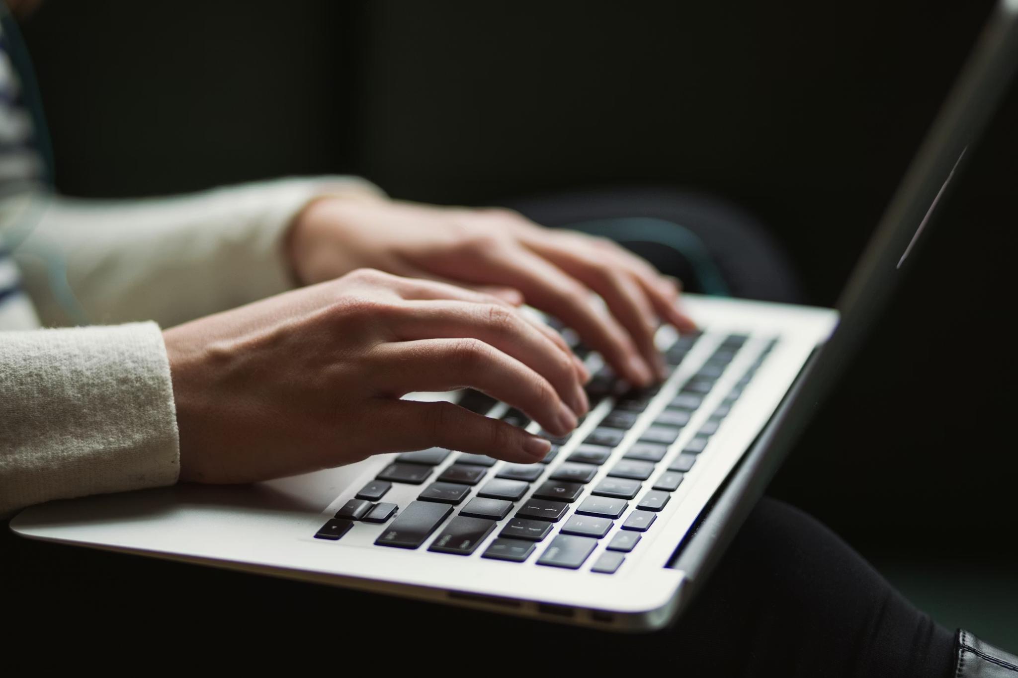Hands typing on a laptop during digital bond trading workflows involving RFQ execution and negotiated settlement processes.