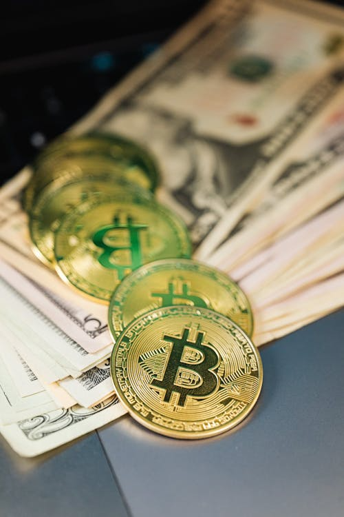 Close-up of several physical Bitcoin tokens placed on paper currency.
