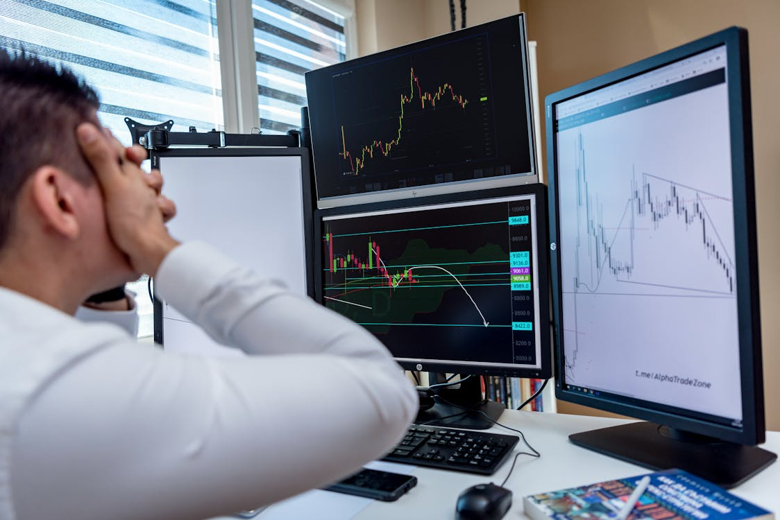 A stressed man looking at the trends displayed on a monitor screen.