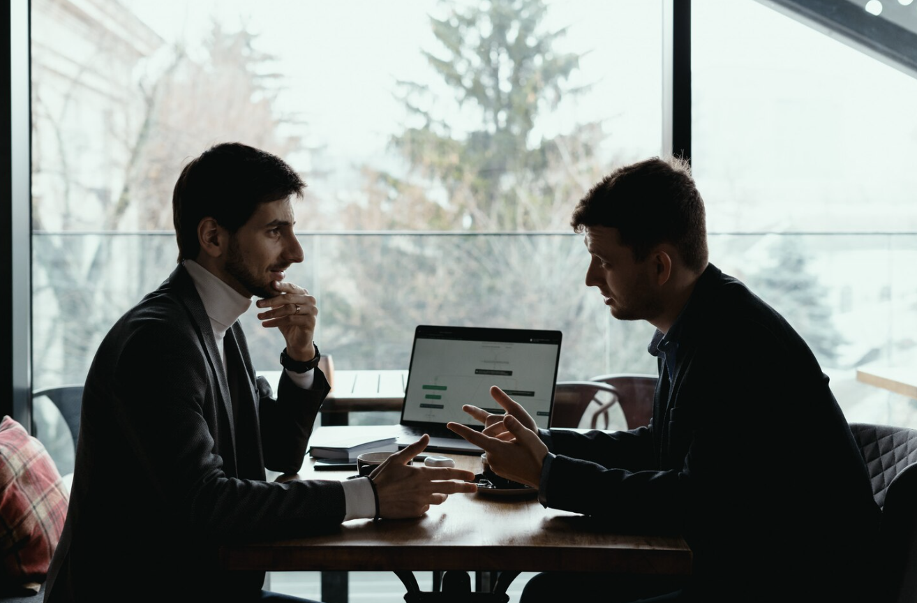 Two investors discussing crypto strategy during a meeting.