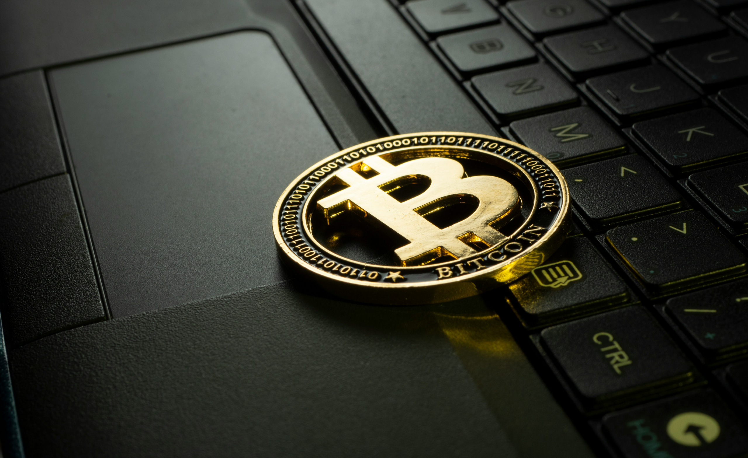 physical bitcoin coin placed on laptop.
