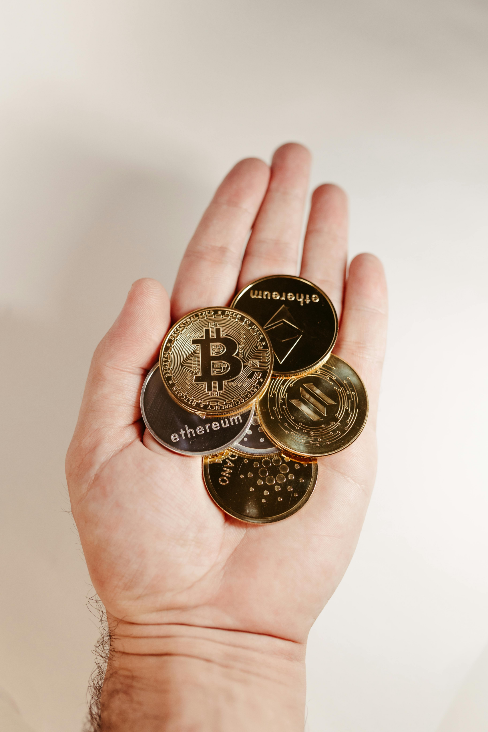 hand holding multiple cryptocurrency coins