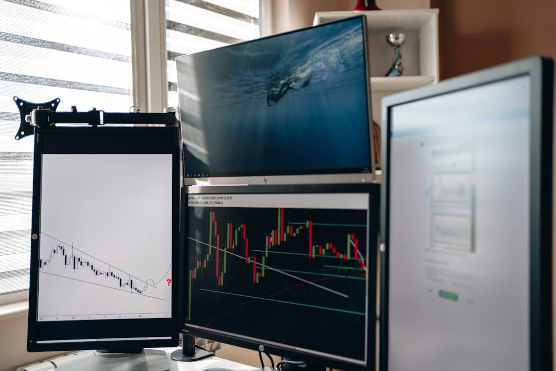 A trading desk setup with multiple screens displaying live cryptocurrency data and analytics dashboards