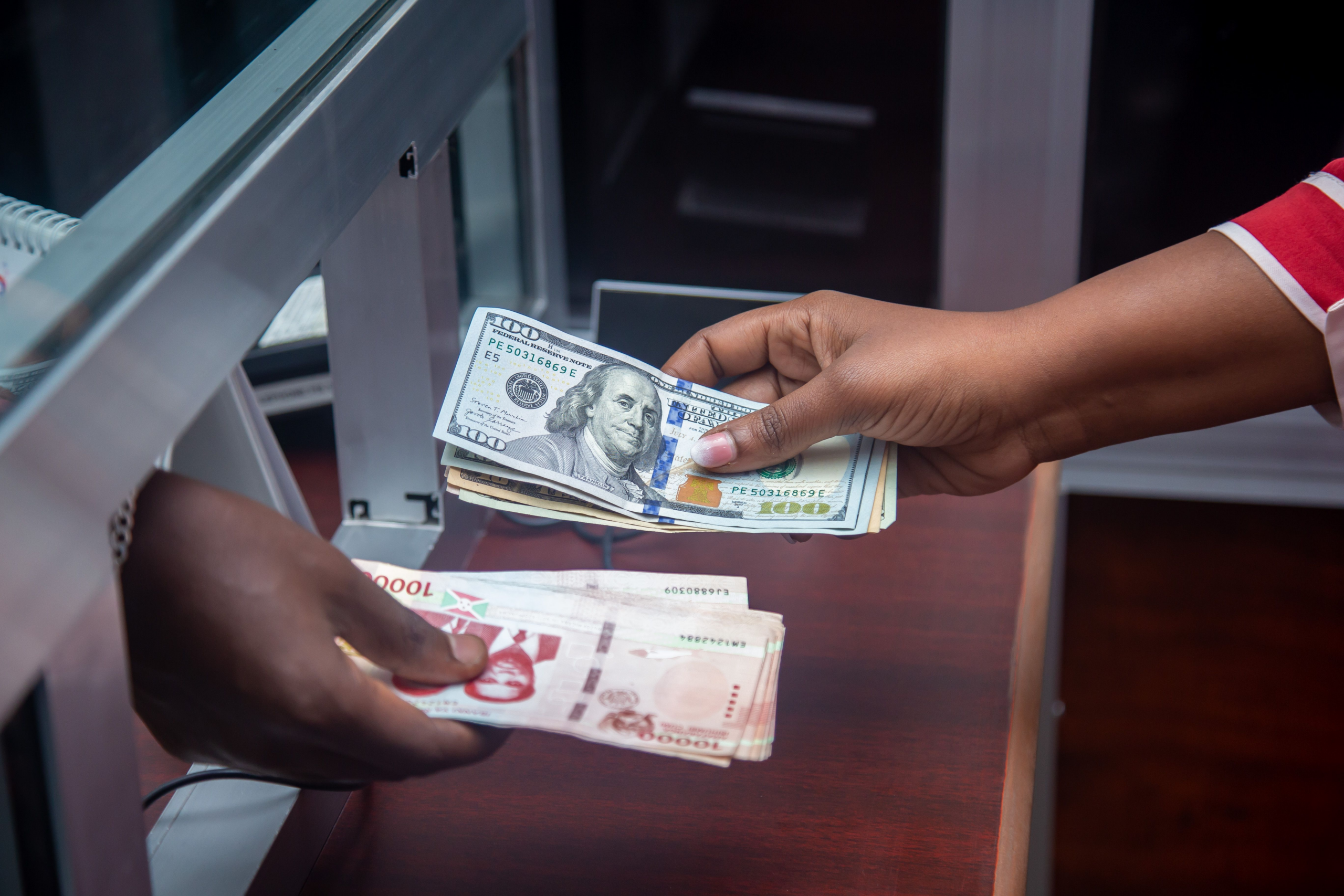 Hands exchanging currencies across a bank counter