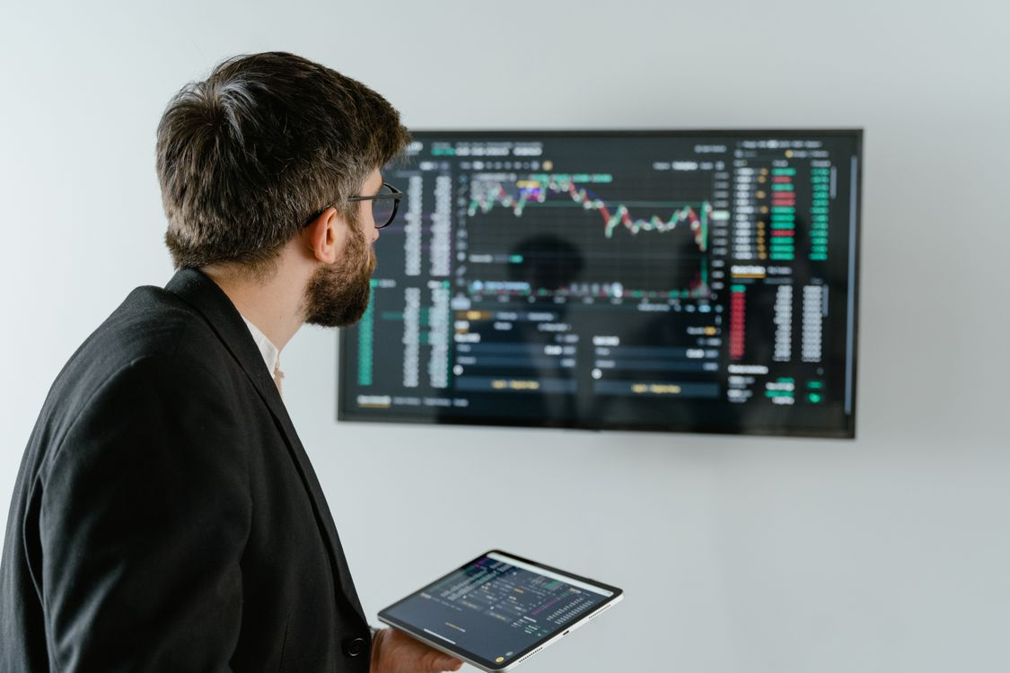 Professional in a suit analyzing financial data charts on a tablet.