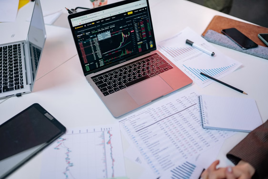 kenson Investments | The Multi-Custodian Imperative Under Regulatory Scrutiny Laptops displaying financial asset performance charts alongside analytical documents on a desk.