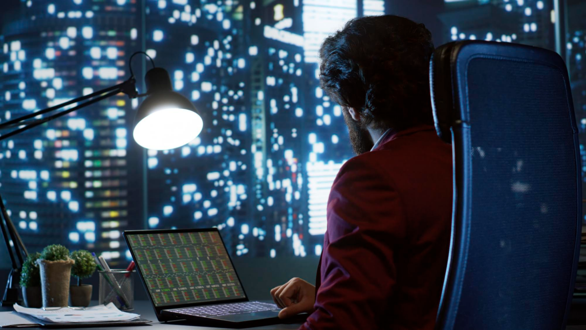 Financial analyst analyzing performance data models on an office desktop computer screen.