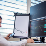 Financial analyst monitoring charts and transaction data across several computer screens