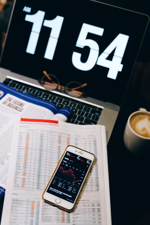 Financial documents and a smartphone displaying regulatory information on a desk.