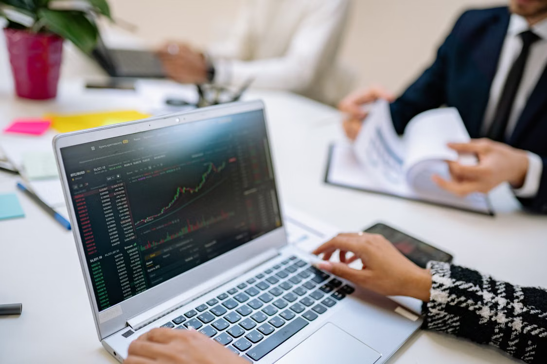 kenson Investments | Stablecoin Rules Are Taking Shape: What Market Participants Should Watch Financial documents and a laptop displaying digital currency market data on a desk.