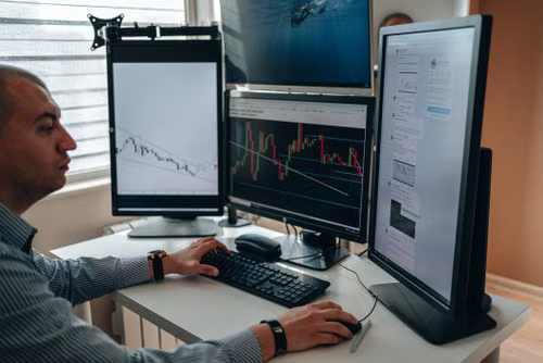 kenson Investments | Stablecoin Rules Are Taking Shape: What Market Participants Should Watch A professional analyzing digital asset market charts on multiple monitors in an office setting.